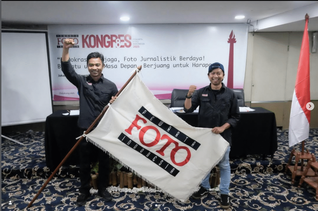 Ketua Umum PFI terpilih Dwi Pambudo dan Sekjen Galih Pradipta mengepalkan tangan sambil membentangkan bendera pataka Pewarta Foto Indonesia usai terpilih aklamasi pada Kongres VIII PFI 2025 di Jakarta.