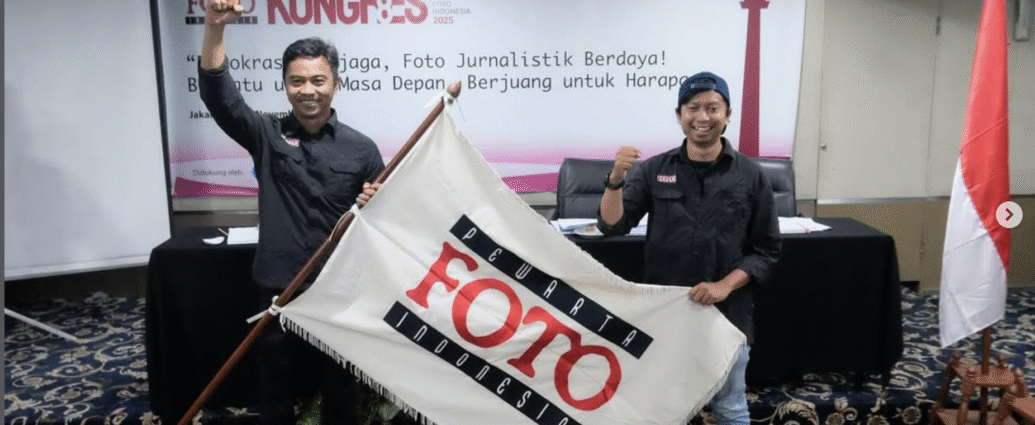 Ketua Umum PFI terpilih Dwi Pambudo dan Sekjen Galih Pradipta mengepalkan tangan sambil membentangkan bendera pataka Pewarta Foto Indonesia usai terpilih aklamasi pada Kongres VIII PFI 2025 di Jakarta.