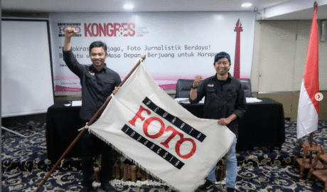 Ketua Umum PFI terpilih Dwi Pambudo dan Sekjen Galih Pradipta mengepalkan tangan sambil membentangkan bendera pataka Pewarta Foto Indonesia usai terpilih aklamasi pada Kongres VIII PFI 2025 di Jakarta.