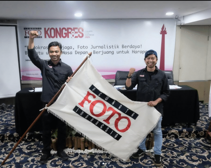 Ketua Umum PFI terpilih Dwi Pambudo dan Sekjen Galih Pradipta mengepalkan tangan sambil membentangkan bendera pataka Pewarta Foto Indonesia usai terpilih aklamasi pada Kongres VIII PFI 2025 di Jakarta.