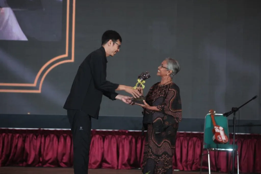 "Piagam penghargaan anumerta 'Lifetime Achievement Award' Anugerah Pewarta Foto Indonesia (APFI) Tahun 2026 berbingkai kayu, diberikan kepada 'Enny Nurhaeni' atas dedikasinya sebagai pewarta foto senior yang berintegritas semasa hidupnya. Piagam ini ditandatangani oleh Ketua Umum PFI Dwi Pambudo di Kabupaten Bogor pada 8 Mei 2026."
