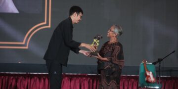 "Piagam penghargaan anumerta 'Lifetime Achievement Award' Anugerah Pewarta Foto Indonesia (APFI) Tahun 2026 berbingkai kayu, diberikan kepada 'Enny Nurhaeni' atas dedikasinya sebagai pewarta foto senior yang berintegritas semasa hidupnya. Piagam ini ditandatangani oleh Ketua Umum PFI Dwi Pambudo di Kabupaten Bogor pada 8 Mei 2026."
