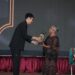 "Piagam penghargaan anumerta 'Lifetime Achievement Award' Anugerah Pewarta Foto Indonesia (APFI) Tahun 2026 berbingkai kayu, diberikan kepada 'Enny Nurhaeni' atas dedikasinya sebagai pewarta foto senior yang berintegritas semasa hidupnya. Piagam ini ditandatangani oleh Ketua Umum PFI Dwi Pambudo di Kabupaten Bogor pada 8 Mei 2026."