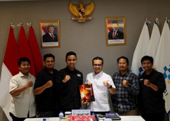 Wamen Komdigi Nezar Patria bersama lima pengurus PFI berfoto bersama mengepalkan tangan tanda semangat di bawah foto resmi Presiden dan Wakil Presiden RI.