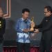 Fauzan (tengah) menerima trofi piala Alex dan Frans Mendur Trophy, penghargaan tertinggi Anugerah Pewarta Foto Indonesia (APFI) 2026, yang diserahkan oleh Wakil Menteri Dalam Negeri Bima Arya (kanan), didampingi oleh Koordinator Dewan Juri Oscar Matuloh (kiri) di atas panggung Auditorium Setda Kabupaten Bogor.