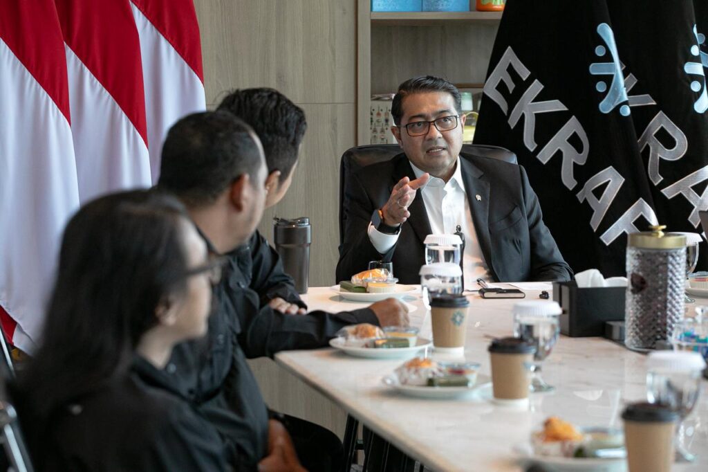 Menteri Ekonomi Kreatif Teuku Riefky Harsya berdiskusi serius sambil menggerakkan tangan kanan di hadapan jajaran pengurus PFI di meja rapat kementerian.