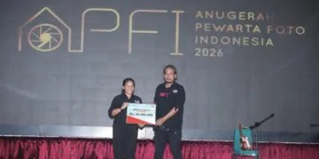 Bendahara Umum PFI Pusat Agriana Ali (kiri) menyerahkan bantuan dana secara simbolis sebesar Rp20.000.000 kepada Koordinator Wilayah Barat PFI Hendra Syamhari untuk program air bersih di Aceh pada acara APFI 2026.