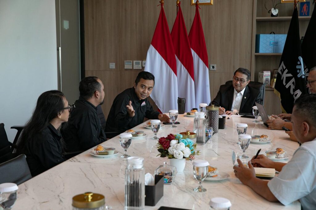 Suasana rapat formal di meja marmer panjang antara jajaran pengurus PFI dan Menekraf Teuku Riefky Harsya yang diapit bendera Merah Putih.