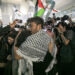 Foto emosional jurnalis Thoudy Badai memeluk erat istrinya di tengah kepungan kilatan kamera wartawan dan kibaran bendera Palestina di bandara.