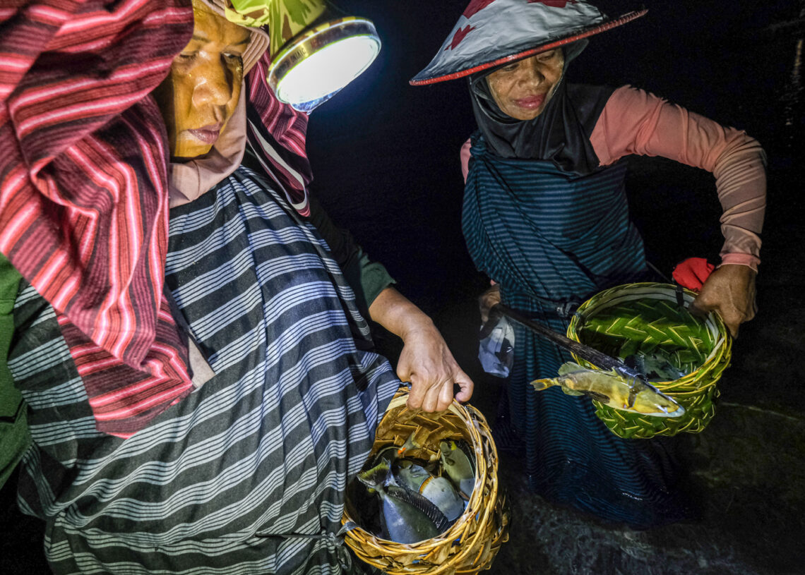 Sejumlah ibu rumah tangga membawa ikan yang ditangkap saat mengikuti tradisi Hekente di Desa Sombu, Wakatobi, Sulawesi Tenggara